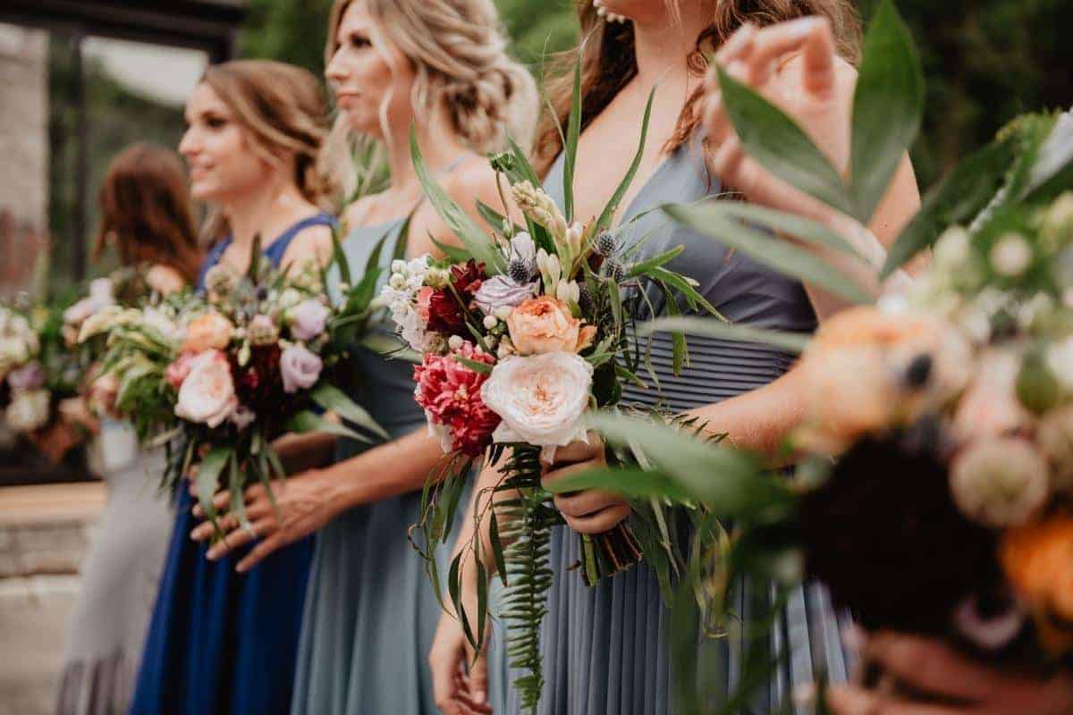 bridesmaids lined up holding bouquets at wedding ceremony. 