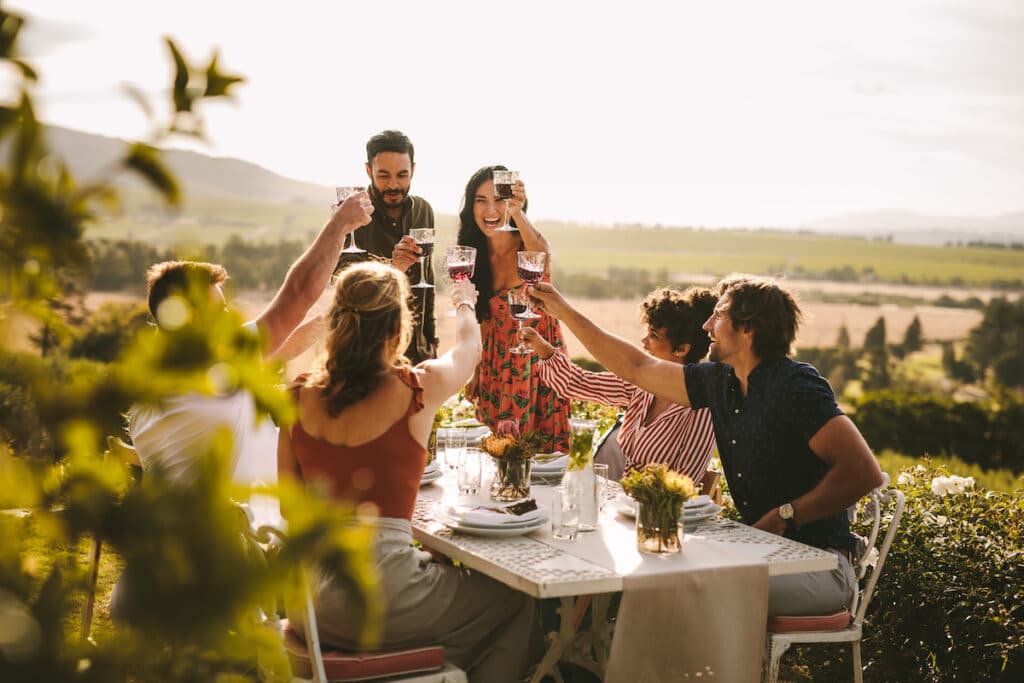 Friends making big party outdoors. Group of people toasting wine during a dinner party.