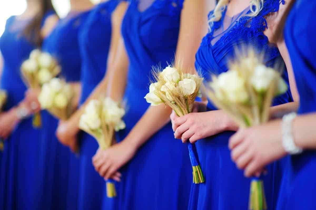 Blue bridesmaid dresses online shopping worn by bridesmaids holding flowers.