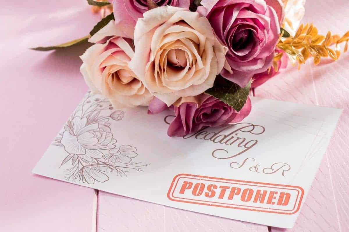 Postponement wedding card with wedding flowers on top.