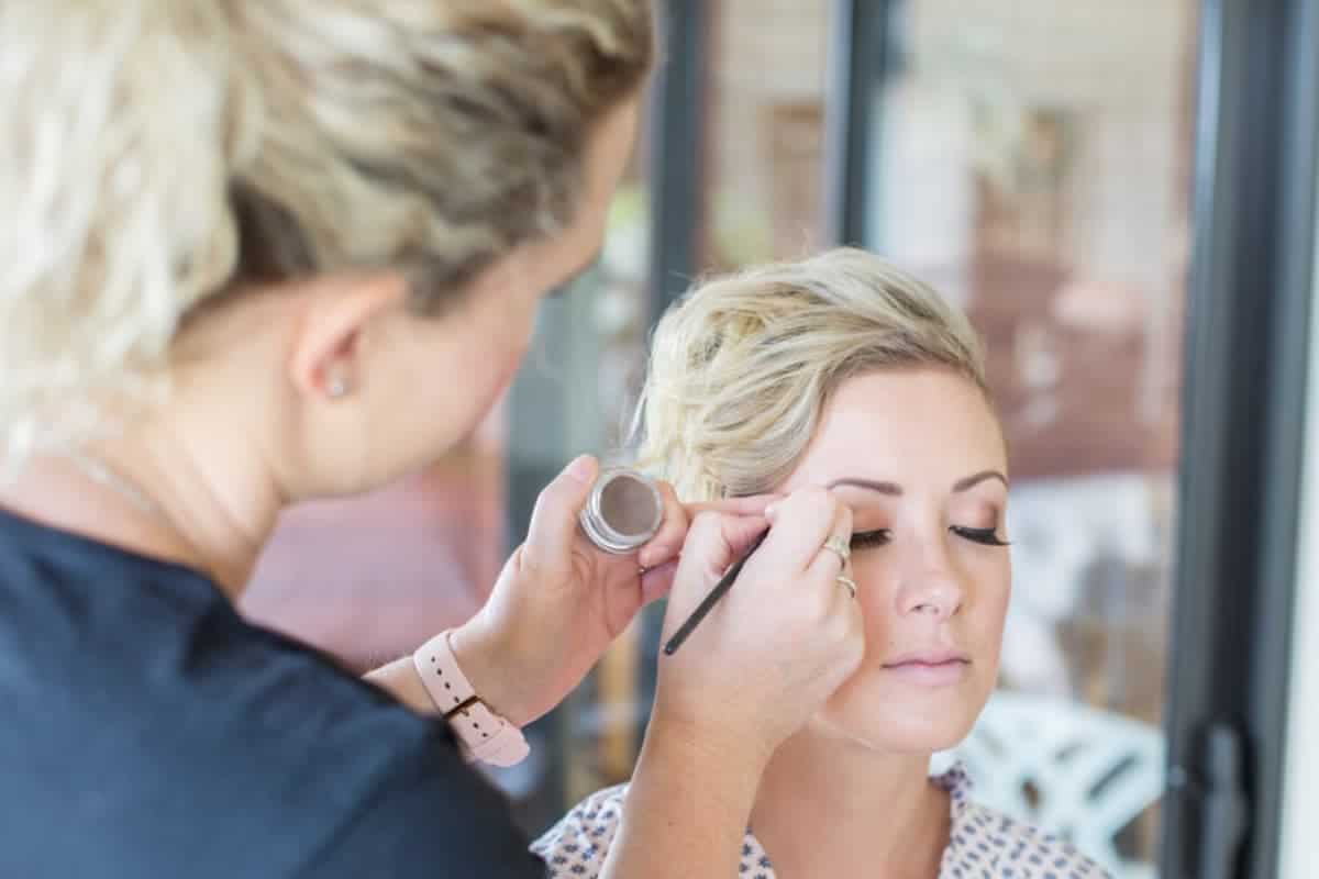 bride having small amount of makeup applied by makeup artist.