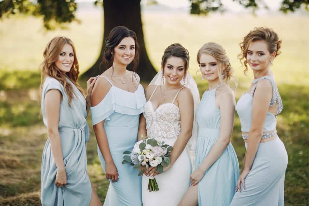 4 bridesmaids with bride each wearing different bridesmaid dress designs but in the same color.
