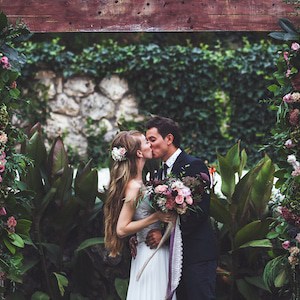 Amazing wedding ceremony with a lot of fresh flowers in Rustic style. Happy newlyweds kissing