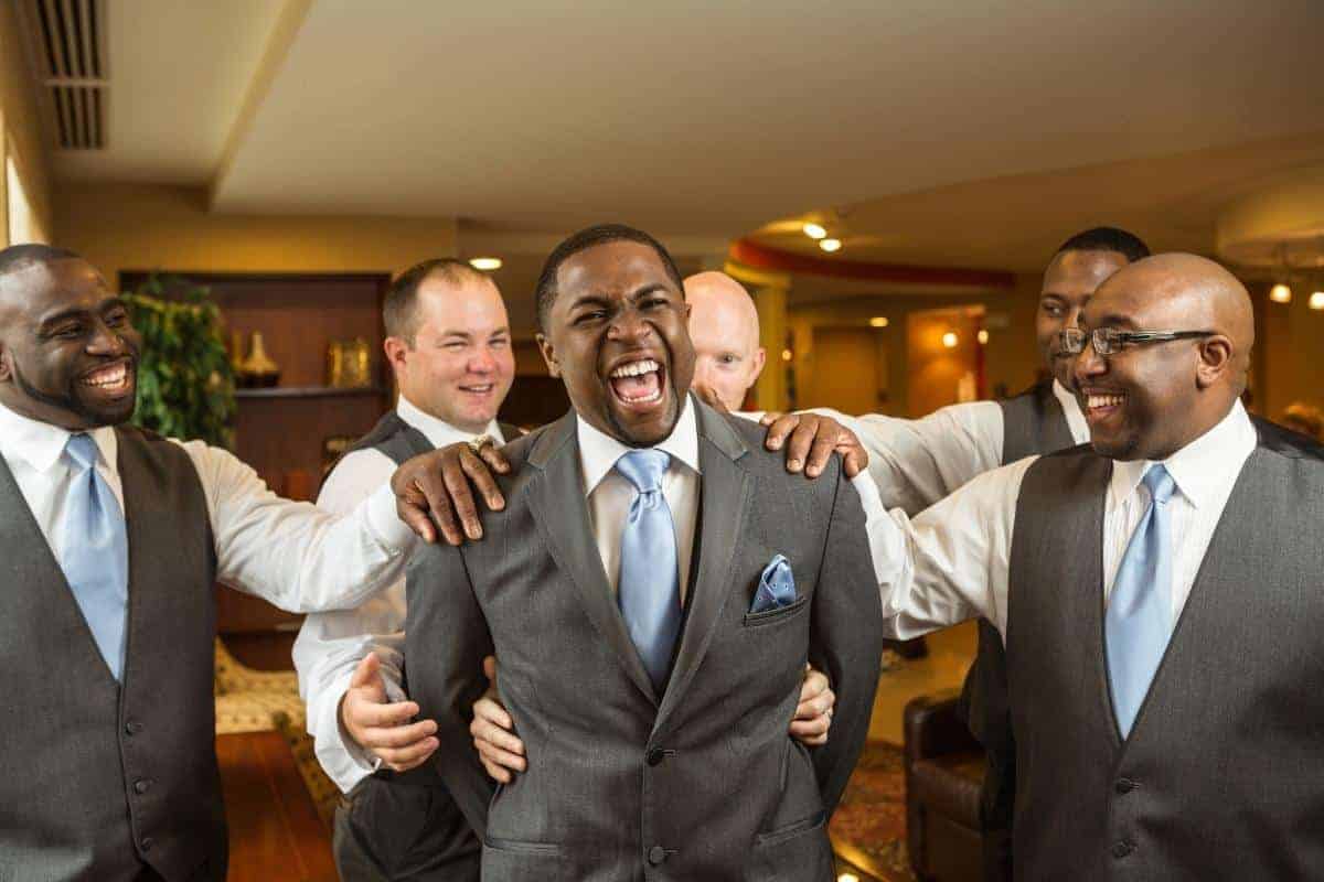 4 groomsmen around the grrom with their hands on his shoulders.