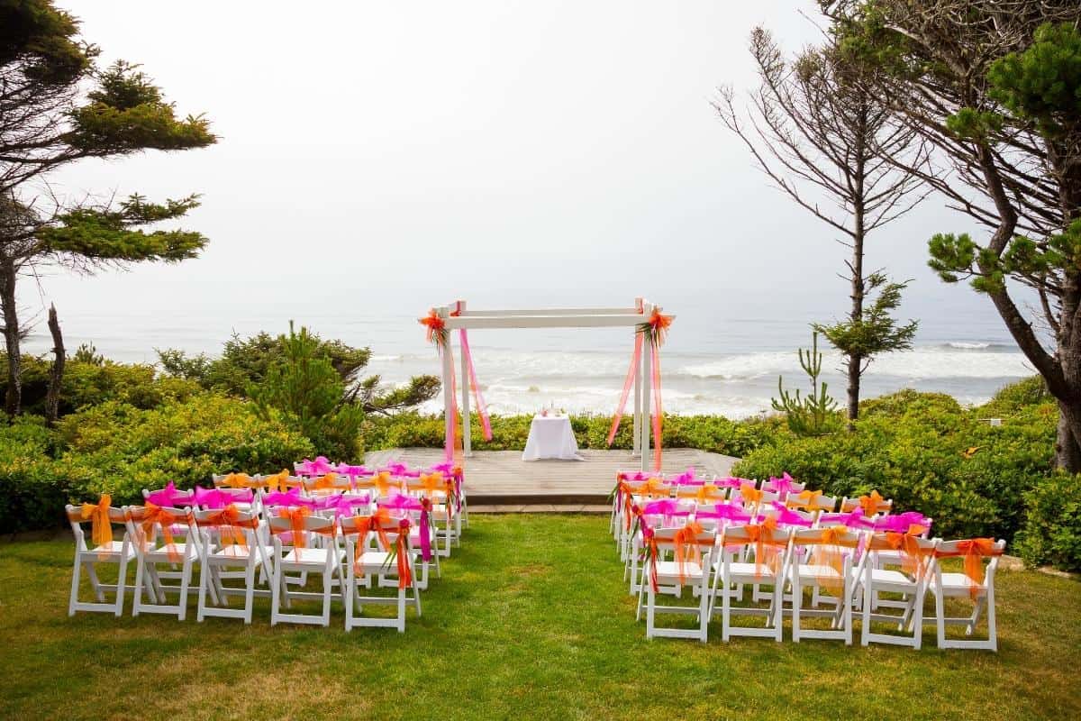 Wedding ceremony by beach with archway and seats.