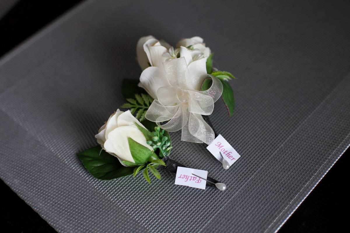 mpther and father boutonniere and corsage on a table.