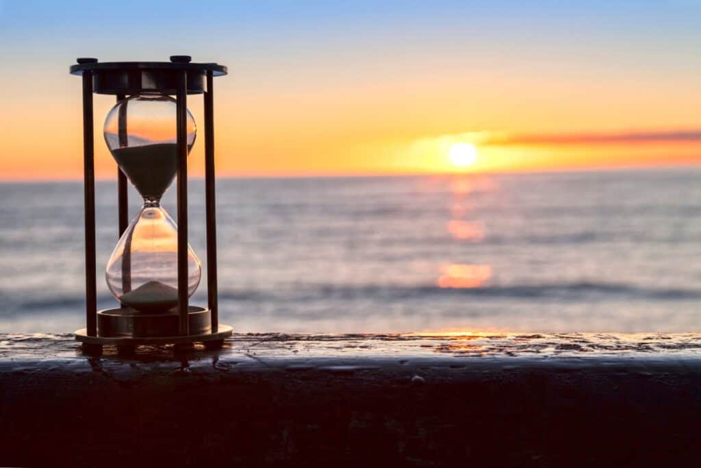 An hourglass with a beach sunset in the background